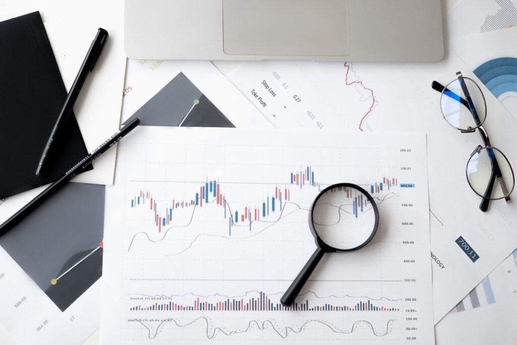 Financial charts on paper with a magnifying glass and glasses on a desk