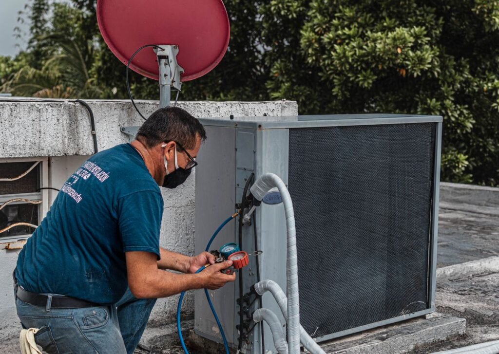 HVAC technician servicing an outdoor air conditioning unit with gauges