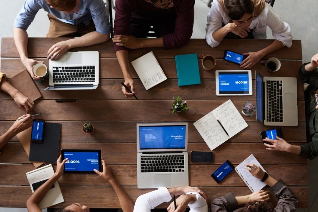 Top-down view of a team working with laptops and tablets around a table