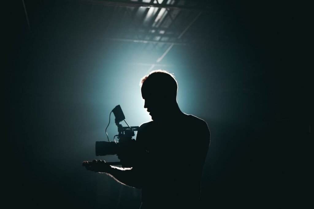 Silhouette of a videographer operating a camera against studio light